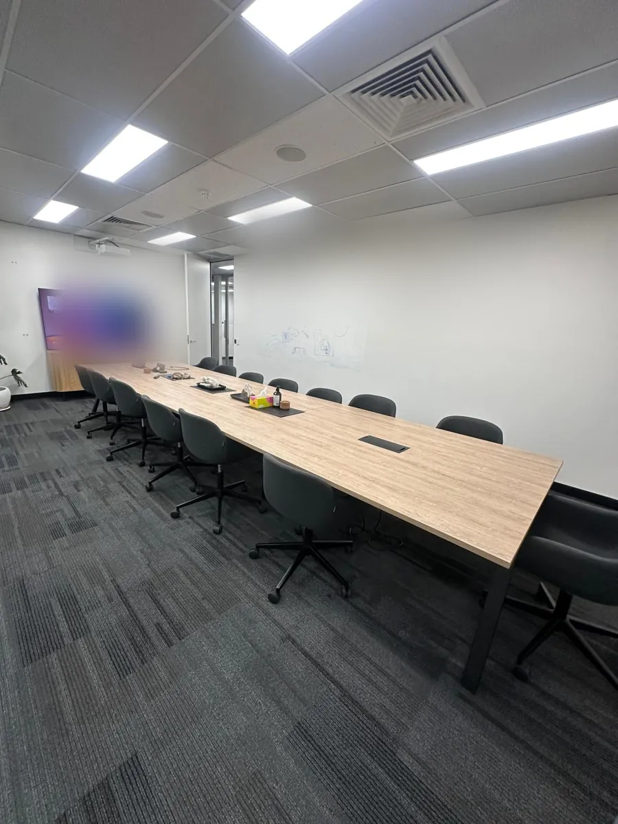 Long boardroom table with black chairs on dark carpet tiles in a Perth CBD office