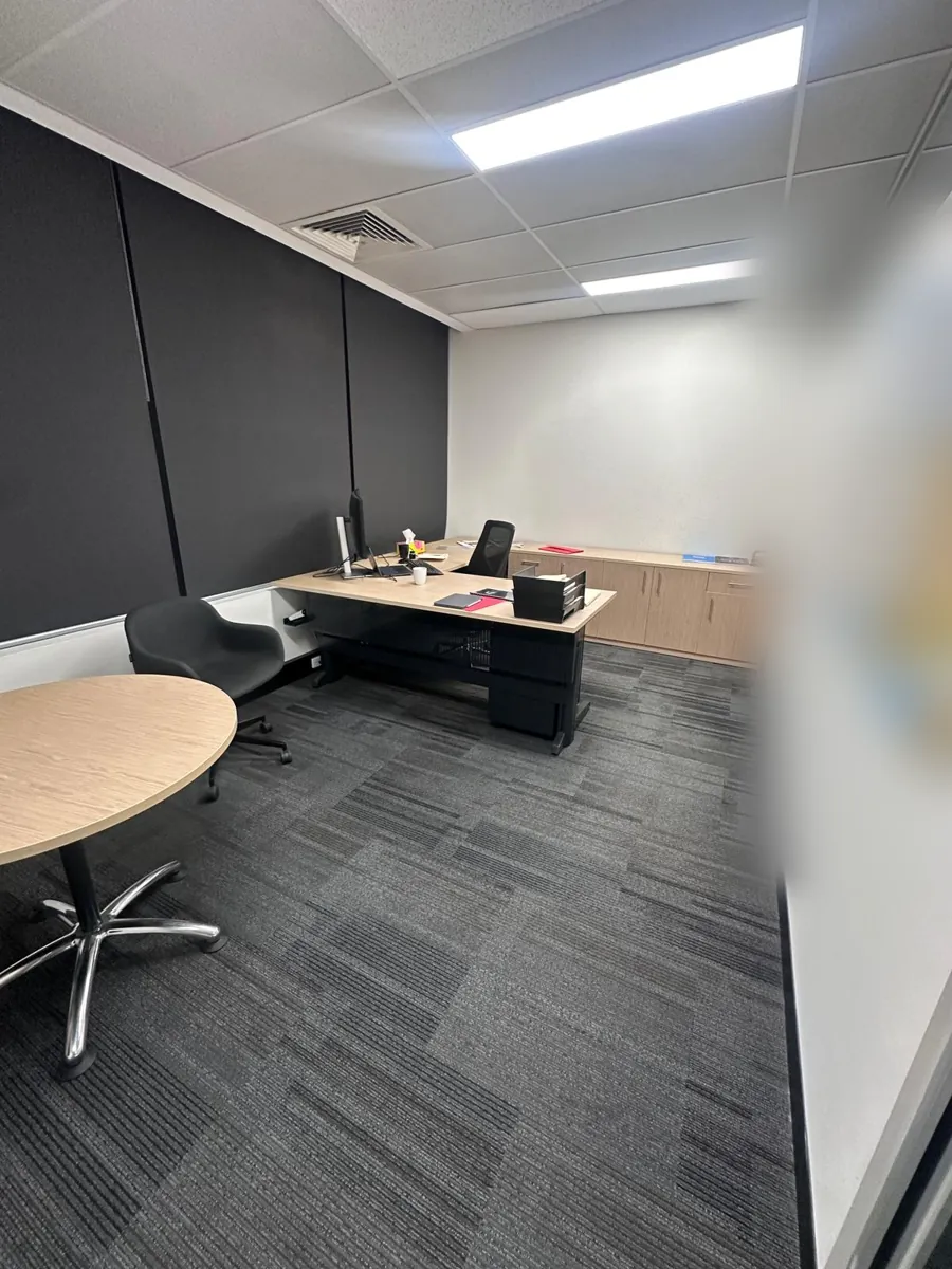 Executive office with a timber desk, round meeting table and dark blinds