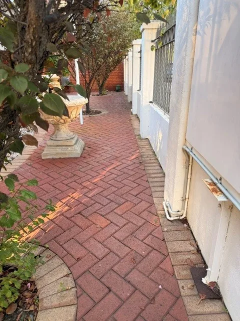 Brick paved side path beside an office building, cleared of leaves and debris
