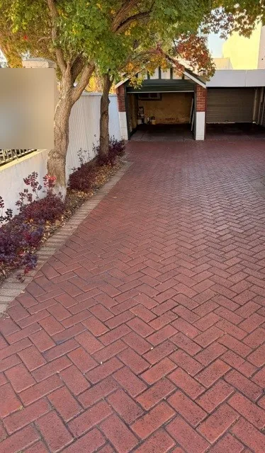 Herringbone brick driveway leading to garages, fully cleared of leaves