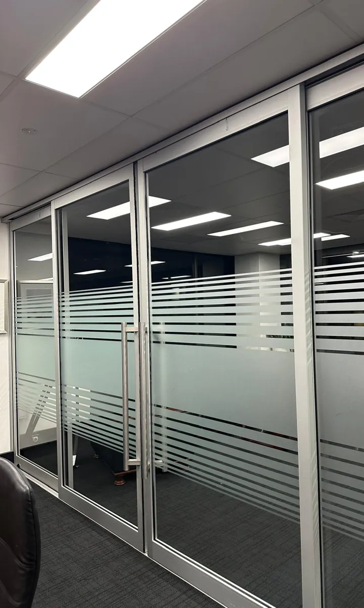 Frosted band glass partitions and doors along an office corridor