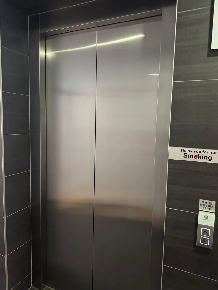 Brushed stainless steel lift doors polished clean in an apartment lobby