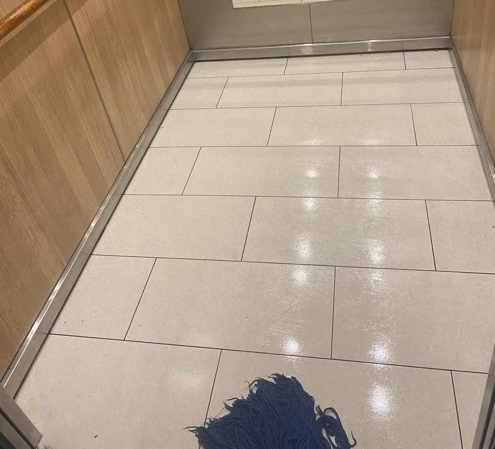 Clean tiled lift car floor with timber panels and handrail after mopping
