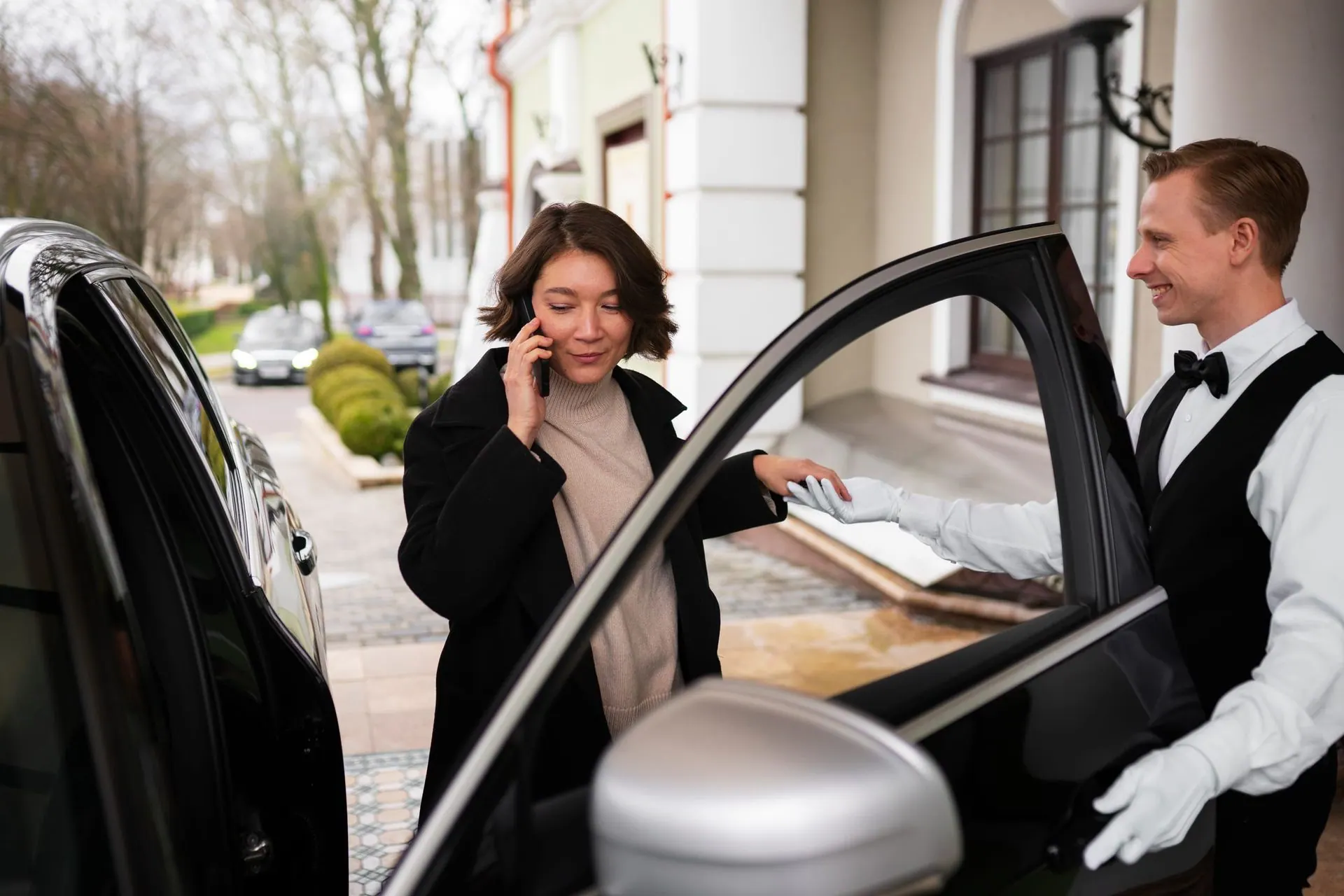 Valet attendant holding a car door open for an arriving guest