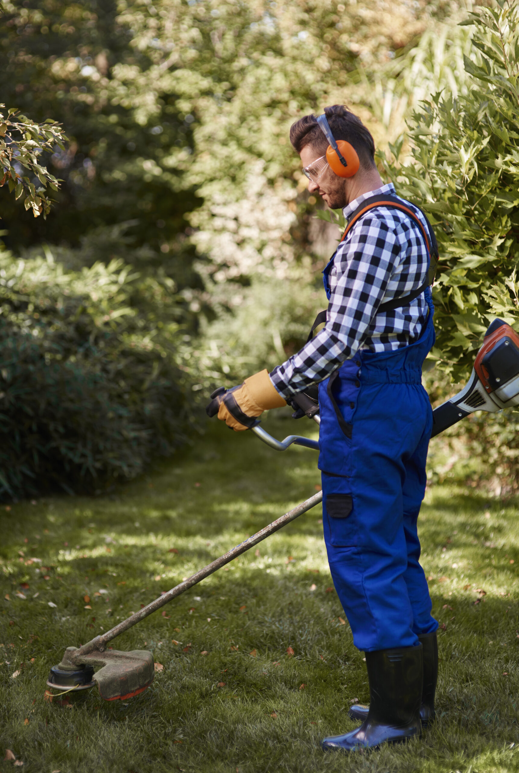 Landscaping specialist inspecting planting beds under integrated property services, ensuring healthy shrubs and soil in strata or commercial grounds.