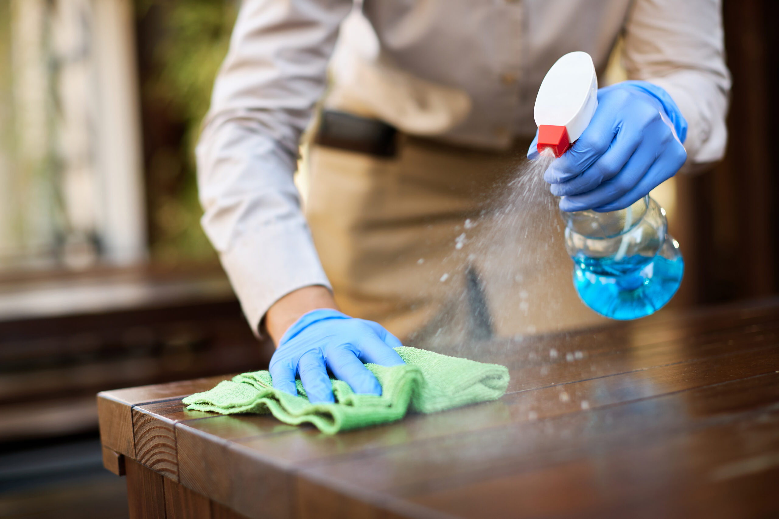 Staff member cleaning and disinfecting glass surfaces and tables