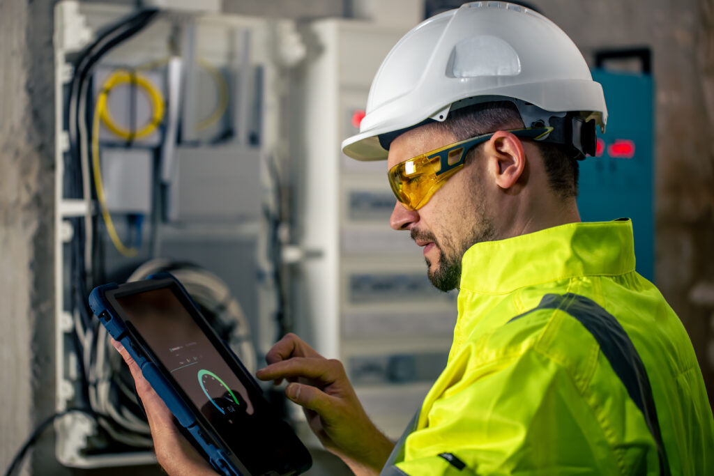 Facilities technician using predictive maintenance software on a tablet in a Perth commercial building plant room